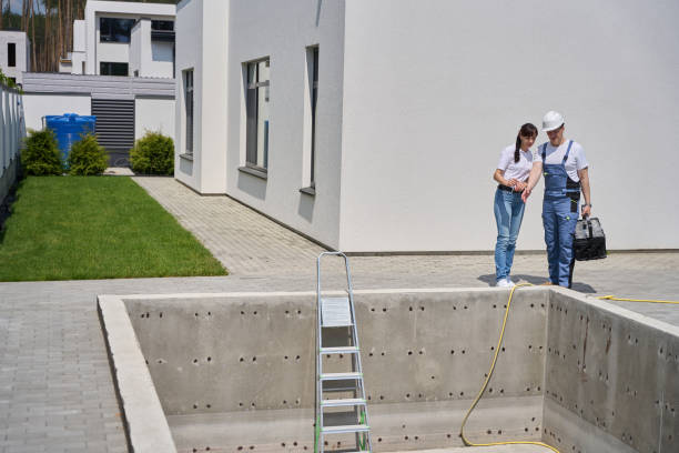 Two individuals standing beside a swimming pool, enjoying the sunny day and the serene atmosphere, with professional pool plastering near Los Angeles ensuring a smooth and safe surface.