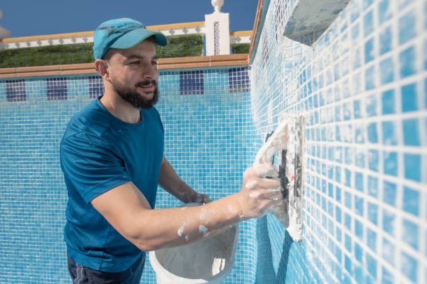 Man spreads the cement grout on the pool tile to waterproof it during a pool remodeling in Eastvale, CA.