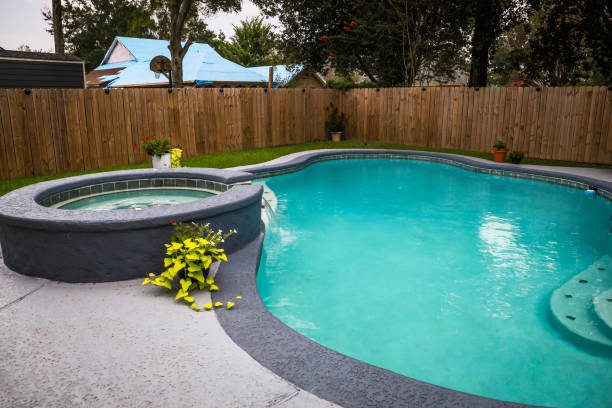 A large freeform gray accent swimming pool with turquoise blue water in a fenced backyard, showcasing a pool remodeling in Eastvale, CA.