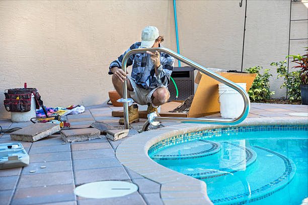 A professional working on pool construction in Eastvale, CA, repairs a swimming pool in a backyard, surrounded by greenery and maintenance tools.