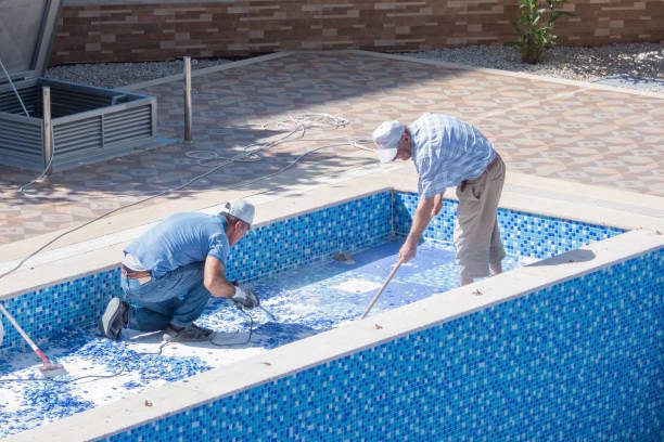 Two men collaborating on the construction of a pool in a residential backyard setting, provided by a top pool replastering service in Riverside, CA.